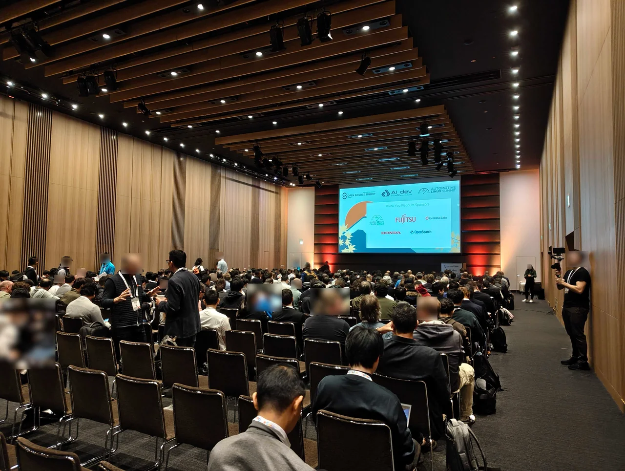 多くの参加者が集まる広々としたメインホールの様子。前方のスクリーンにはプラチナスポンサーの企業ロゴが表示されている
